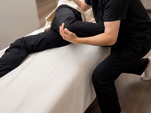 Close-up of a practitioner's hands supporting a person's bent knee during osteopathic treatment